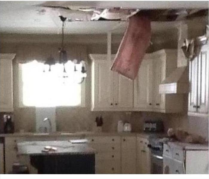 hanging insulation and debris from a damaged ceiling in a kitchen