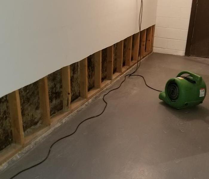 Drywall missing from the bottom of a wall with SERVPRO equipment on the floor