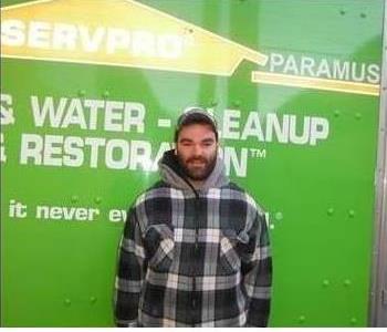 employee posing in a plaid jacket in front of truck