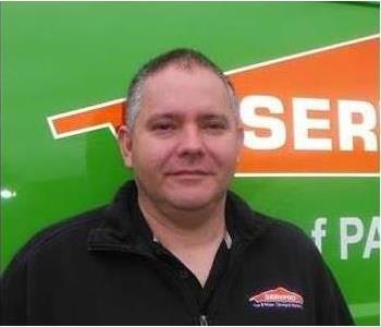 Owner in black SERVPRO shirt posing in front of logo truck