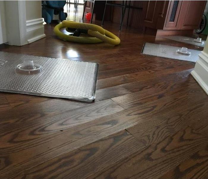water damaged hardwood floors with drying mats setup