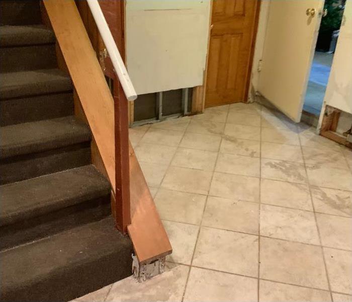 Water damaged room with tile and drywall removed from the bottom of the wall