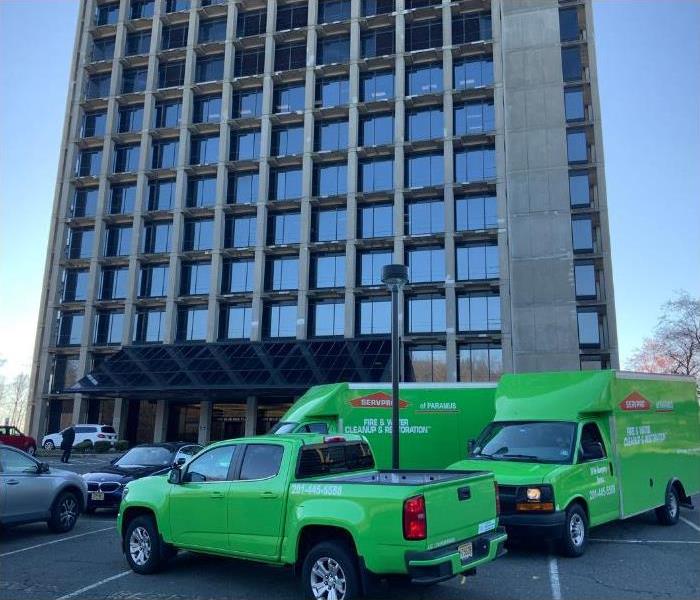 SERVPRO vehicles in a parking lot in front of a tall building