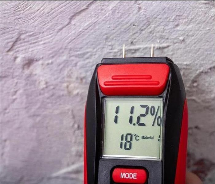 red moisture meter by a stucco wall