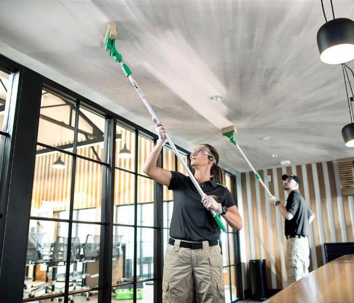 SERVPRO technicians removing soot damage from a ceiling with sponges